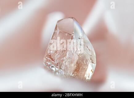 Cristallo trasparente naturale di topazio di vino chiaro e prezioso su sfondo rosa Foto Stock