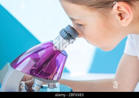 Una ragazza esamina un'ala di una mosca sotto un microscopio Foto Stock