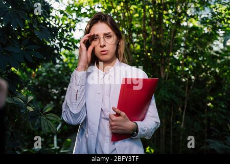 Giovane ingegnere agricolo che lavora in serra. Giovane scienziata femminile che guarda la macchina fotografica Foto Stock