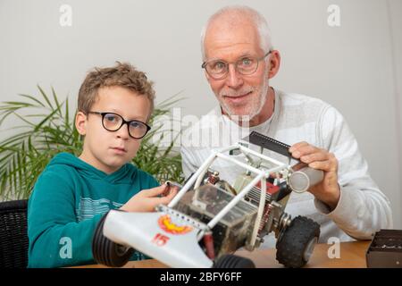 nonno e figlio ragazzino che riparano a casa un modello di auto radiocomandata Foto Stock