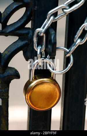 lucchetto e robusta catena in acciaio avvolta intorno al cancello di ingresso in metallo Foto Stock