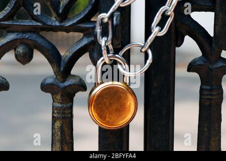 lucchetto e robusta catena in acciaio avvolta intorno al cancello di ingresso in metallo Foto Stock