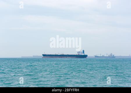 Navi da carico, petroliere e navi portarinfuse ancorate al tramonto lungo il rettilineo di Singapore Foto Stock