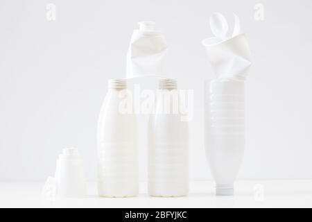 Composizione minima di bottiglie di plastica bianche e articoli su sfondo bianco, concetto di smistamento e riciclaggio dei rifiuti Foto Stock