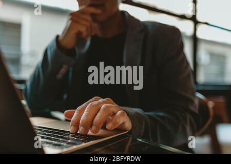 Primo piano di un uomo d'affari che lavora su un notebook. Mano di un dirigente maschile che lavora su un computer portatile in ufficio. Foto Stock