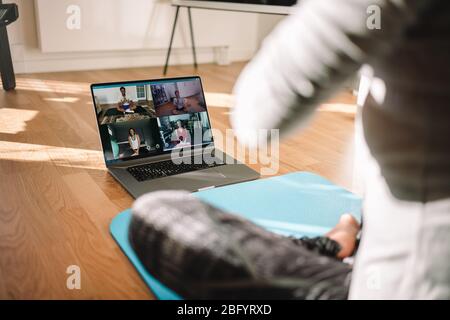 Vista di una donna che conduce una lezione virtuale di fitness con un gruppo di persone a casa durante una videoconferenza. Istruttore di fitness che tiene lezioni di yoga online ove Foto Stock