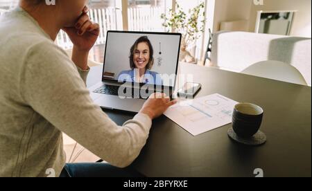 Donna teleconferenza con collega femmina su laptop. Colleghi che lavorano da casa per videochiamare e discutere di lavoro. Foto Stock