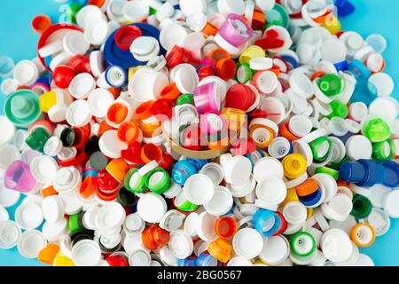 Vista dall'alto di un numero enorme di tappi in plastica per bottiglie di diverse dimensioni, forme e colori. Concetto di riciclaggio della plastica. Foto Stock