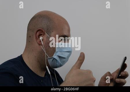 uomo calvo in una maschera fare una videochiamata con le cuffie Foto Stock