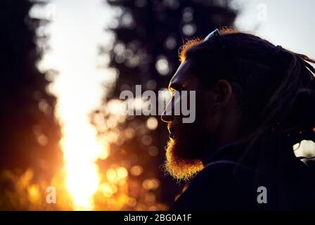 Silhouette uomo con Dreadlocks nel tramonto di foreste di montagna Foto Stock