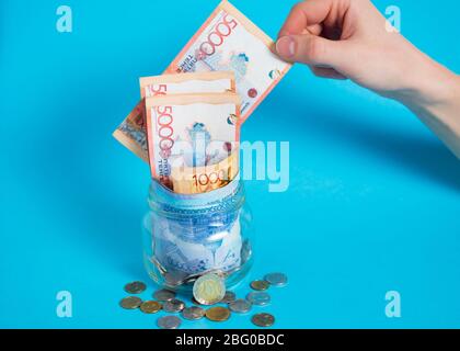 Tinge fuori da un vaso di vetro. Mettere i soldi in un vaso di vetro. Kazakistan, KZ, KZT. Banconote, banconote, monete, Banca. Stipendio, credito, risparmio, paga e s Foto Stock