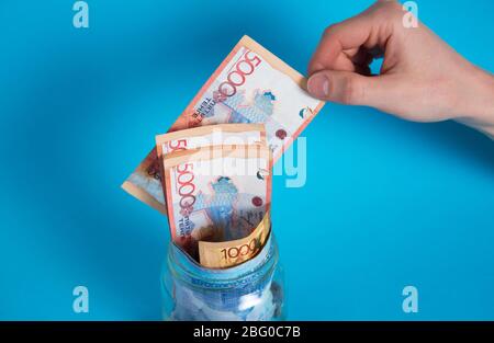 Tinge fuori da un vaso di vetro. Mettere i soldi in un vaso di vetro. Kazakistan, KZ, KZT. Banconote, banconote, monete, Banca. Stipendio, credito, risparmio, paga e s Foto Stock