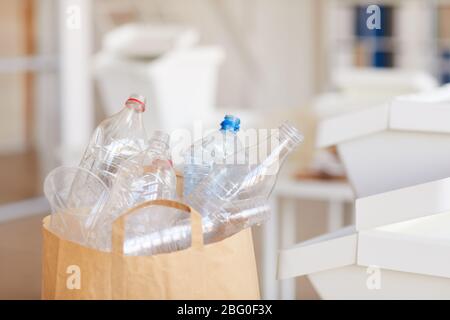 Immagine di sfondo ravvicinata delle bottiglie di plastica scartate in un sacchetto di carta pronto per il riciclaggio nell'interno domestico, spazio per le copie Foto Stock