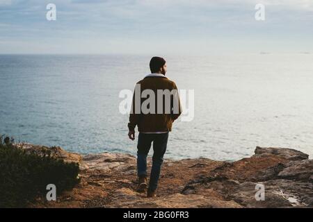 Ritratto di giovane uomo che cammina al mare all'aperto Foto Stock