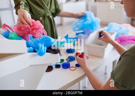 Primo piano di persone non riconoscibili che smistano i rifiuti di plastica a casa prima di riciclarli, spazio per la copia Foto Stock