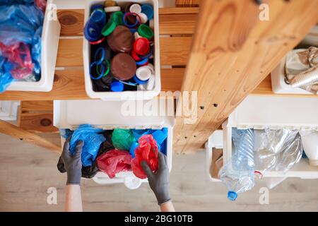 Vista ad angolo elevato del rack per scaffali in legno con contenitori in plastica per lo smistamento dei rifiuti a casa, concetto di stoccaggio e riciclaggio, spazio per copie Foto Stock