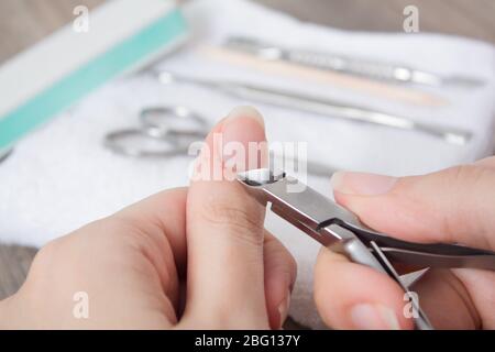 Una donna fa un manicure a casa. Attrezzi di manicure. Manicure bordato. Tagliare, ferite al dito, sangue. Manicure pericoloso. Cura della casa, Spa, bellezza. Chiodo sal Foto Stock