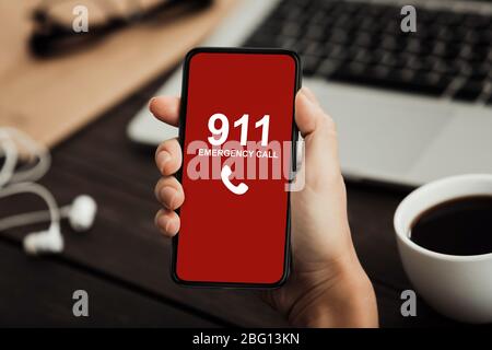 Lavoratore che detiene uno smartphone con numero di emergenza Foto Stock