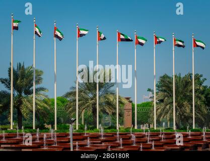 Bandiere degli Emirati Arabi Uniti che sventolano sui pali contro il cielo blu di fronte all'hotel ad Abu Dhabi. Foto Stock