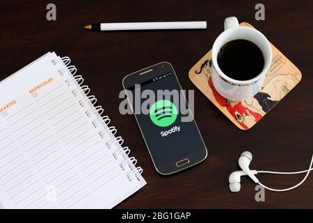 Telefono cellulare sulla scrivania con l'applicazione Spotify sullo schermo. App per lo streaming di musica. Foto Stock