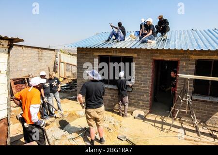 Soweto, Sudafrica - 05 settembre 2009: Programma diversificato di Comunità di Outreach che aiuta ad installare tetto di metallo su una piccola casa a prezzi accessibili in locale a. Foto Stock