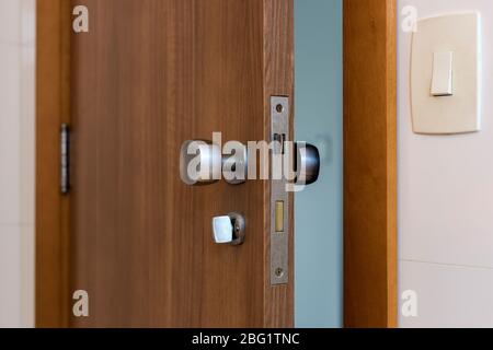 Porta in legno di un bagno. Primo piano del blocco metallico. Porta singola interna in compensato. Foto Stock