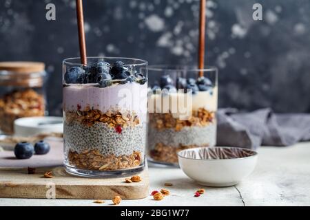 Colazione con chia, granola, frutti di bosco e yogurt in un bicchiere. Stalla il dessert in un bicchiere. Foto Stock