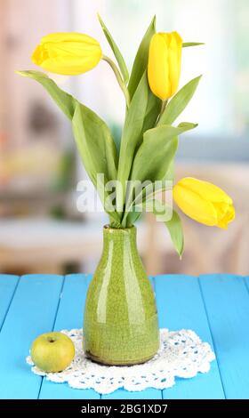 Tulipani gialli in vaso su tavolo di legno sullo sfondo della stanza Foto Stock