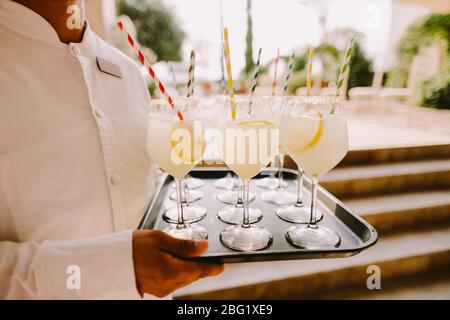 cameriere che tiene bicchieri con cocktail caldo estate. Blarmen con cocktail di limonata ghiacciata. Foto Stock