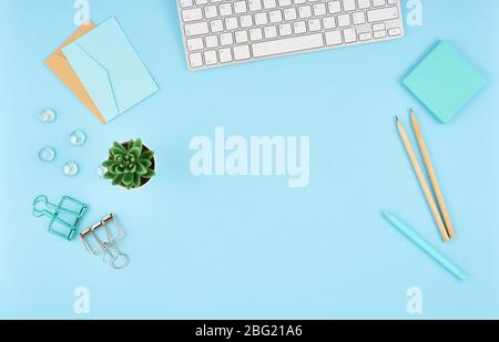 Desktop blu per ufficio. Vista dall'alto di un moderno e luminoso tavolo con accessori da ufficio, tastiera Foto Stock