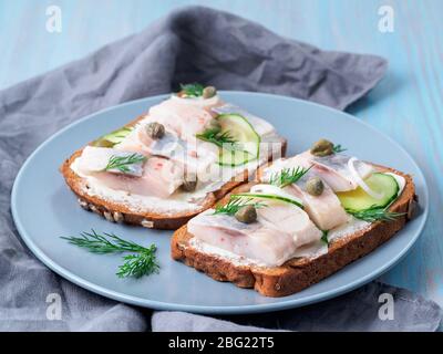 Aringa smorrebrod - tradizionali panini danesi. Pane di segale nero con aringa Foto Stock