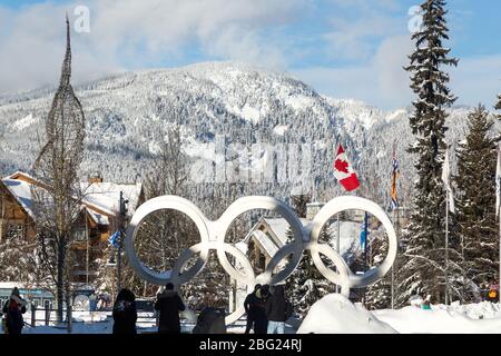 WHISTLER, BC, CANADA - 17 GENNAIO 2020: Gli anelli olimpici situati nel villaggio di Whistler con i turisti che scattano le foto e la bandiera canadese. Foto Stock