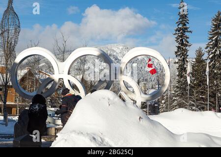 WHISTLER, BC, CANADA - 17 GENNAIO 2020: Gli anelli olimpici situati nel villaggio di Whistler con i turisti che scattano le foto e la bandiera canadese. Foto Stock