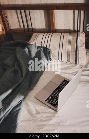 Lavoro da casa. Il computer portatile si trova sul letto. Una pausa durante il lavoro. Foto Stock