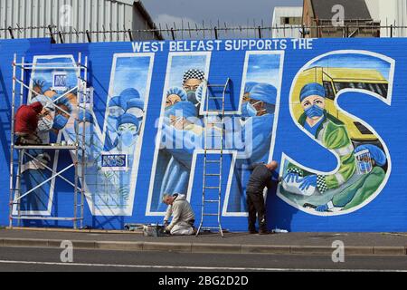 BELFAST 18/04/2020. Gli artisti di Belfast occidentale del West Belfast Festival hanno messo i tocchi finali di un nuovo murale che sostiene i lavoratori del NHS sulla International Peacewall on the Falls Road, a ovest di Belfast, durante questo blocco Covid-19 a Belfast, Irlanda del Nord. Sono state registrate 17 morti che hanno portato il numero di morti a 193 annunciato dall'Agenzia per la sanità pubblica. Foto/Paul McErlane Foto Stock