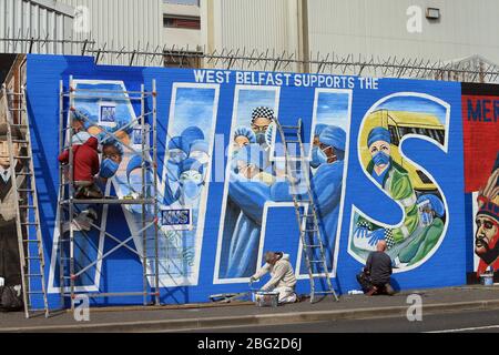 BELFAST 18/04/2020. Gli artisti di Belfast occidentale del West Belfast Festival hanno messo i tocchi finali di un nuovo murale che sostiene i lavoratori del NHS sulla International Peacewall on the Falls Road, a ovest di Belfast, durante questo blocco Covid-19 a Belfast, Irlanda del Nord. Sono state registrate 17 morti che hanno portato il numero di morti a 193 annunciato dall'Agenzia per la sanità pubblica. Foto/Paul McErlane Foto Stock