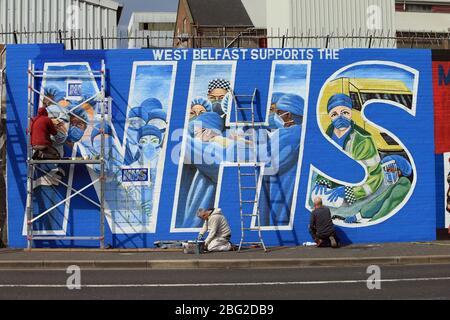 BELFAST 18/04/2020. Gli artisti di Belfast occidentale del West Belfast Festival hanno messo i tocchi finali di un nuovo murale che sostiene i lavoratori del NHS sulla International Peacewall on the Falls Road, a ovest di Belfast, durante questo blocco Covid-19 a Belfast, Irlanda del Nord. Sono state registrate 17 morti che hanno portato il numero di morti a 193 annunciato dall'Agenzia per la sanità pubblica. Foto/Paul McErlane Foto Stock