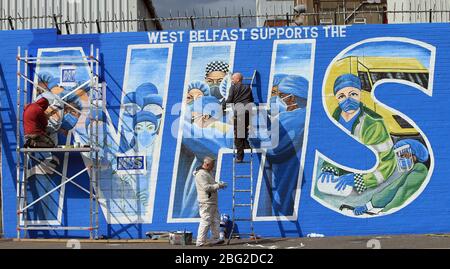 BELFAST 18/04/2020. Gli artisti di Belfast occidentale del West Belfast Festival hanno messo i tocchi finali di un nuovo murale che sostiene i lavoratori del NHS sulla International Peacewall on the Falls Road, a ovest di Belfast, durante questo blocco Covid-19 a Belfast, Irlanda del Nord. Sono state registrate 17 morti che hanno portato il numero di morti a 193 annunciato dall'Agenzia per la sanità pubblica. Foto/Paul McErlane Foto Stock