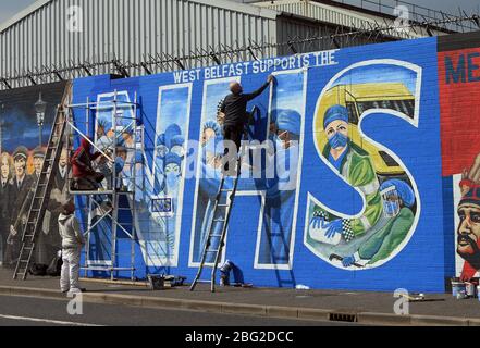 BELFAST 18/04/2020. Gli artisti di Belfast occidentale del West Belfast Festival hanno messo i tocchi finali di un nuovo murale che sostiene i lavoratori del NHS sulla International Peacewall on the Falls Road, a ovest di Belfast, durante questo blocco Covid-19 a Belfast, Irlanda del Nord. Sono state registrate 17 morti che hanno portato il numero di morti a 193 annunciato dall'Agenzia per la sanità pubblica. Foto/Paul McErlane Foto Stock