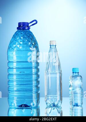 Bottiglie d'acqua diverse su sfondo blu Foto Stock