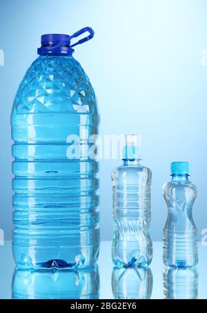 Bottiglie d'acqua diverse su sfondo blu Foto Stock