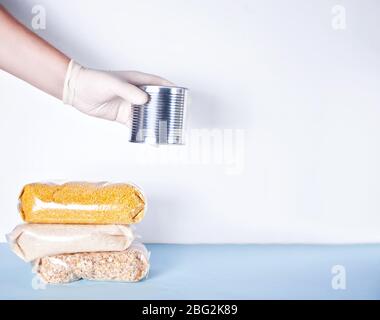 Le mani da uomo con guanti in gomma danno lattina con cibo. Donazione di cibo. Consegna di cibo durante un'epidemia. Consegna del prodotto senza contatto. Spazio di copia. Foto Stock