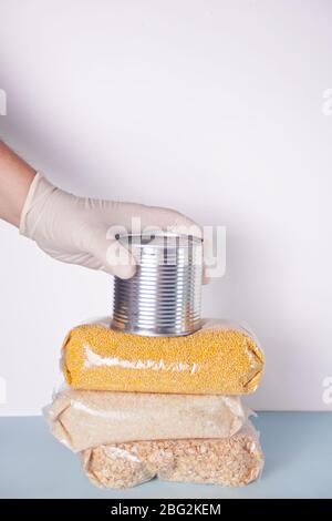 Le mani da uomo con guanti in gomma danno lattina con cibo. Donazione di cibo. Consegna di cibo durante un'epidemia. Consegna del prodotto senza contatto. Spazio di copia. Foto Stock