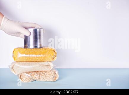 Le mani da uomo con guanti in gomma danno lattina con cibo. Donazione di cibo. Consegna di cibo durante un'epidemia. Consegna del prodotto senza contatto. Spazio di copia. Foto Stock