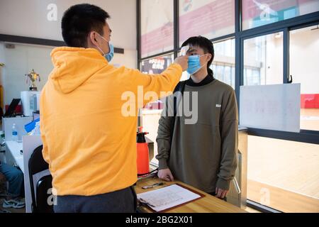 Changsha, provincia cinese Hunan. 20 aprile 2020. Un uomo ha la sua temperatura controllata prima di entrare in un campo da basket in un centro sportivo Changsha, provincia di Hunan della Cina meridionale, 20 aprile 2020. Credit: Chen Sihan/Xinhua/Alamy Live News Foto Stock