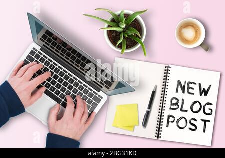 Blog e creazione di contenuti concetto, testo NUOVO POST SUL BLOG di blocco note accanto a persona che lavora sul computer portatile Foto Stock