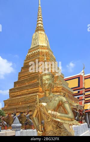 Statua di Kinnara (creatura mitologica, mezzo uccello, mezza donna) accanto al chedi d'oro a Wat Phra Kaew, Bangkok, Thailandia Foto Stock
