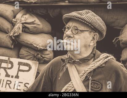 Vecchio stile, vista mono di uomo vestito come warden ARP anni '40 isolato all'aperto da rifugio, Severn Valley Railway 1940 WWII evento estivo, Regno Unito Foto Stock