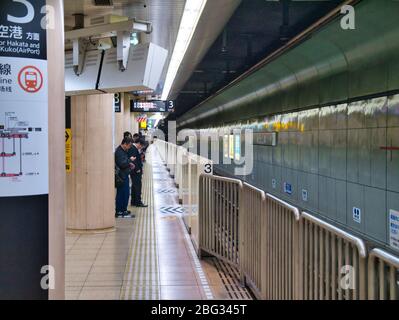 I pendolari attendono in una stazione metropolitana di Fukuoka, Giappone. Foto Stock