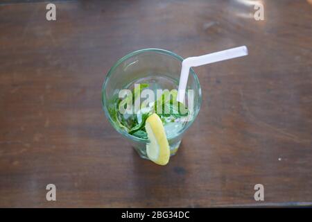 Vista dall'alto di un bicchiere vuoto con lime, menta, paglia e mojito di ghiaccio bere su un tavolo. Foto Stock